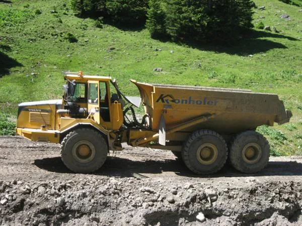 Knickgelenkter Muldenkipper mit Kronhofer-Beschriftung auf einer Baustelle am Berghang