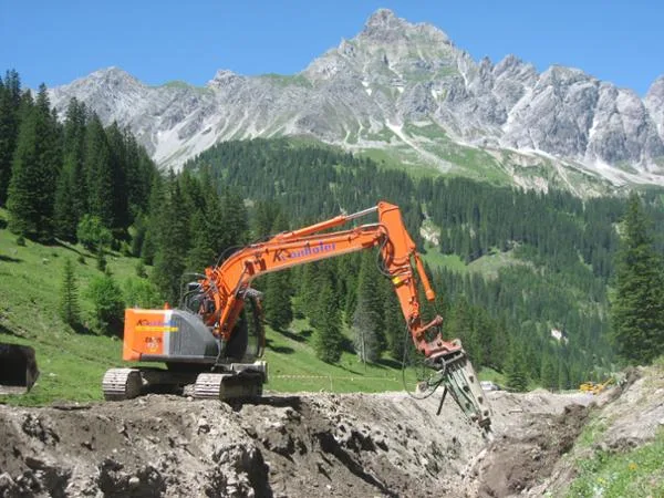 Kettenbagger mit Hydraulikhammer und Kronhofer-Beschriftung vor einer Felswand